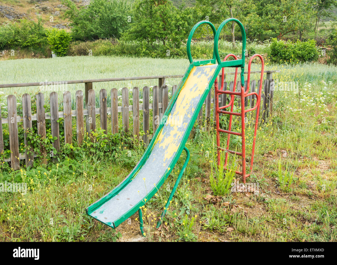 Children`s slide in overgrown playground in rural village in Spain